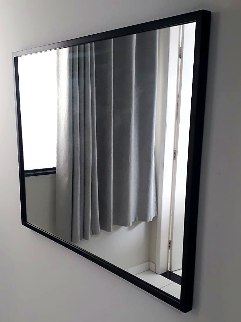 Espelho horizontal com moldura preta refletindo uma cortina